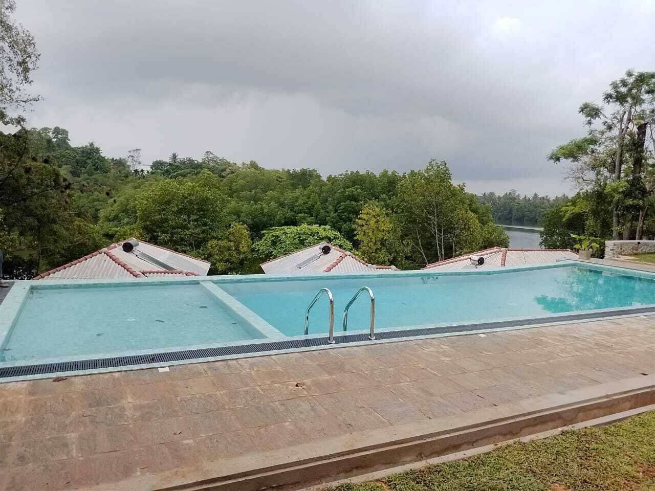 A rectangular swimming pool with two ladders, surrounded by a paved deck.