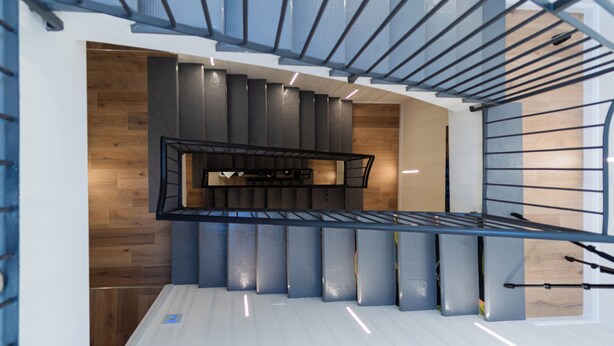 A modern interior with a staircase, wooden panel walls, and a metal railing. - Le Suite del Corso (Lugo)
