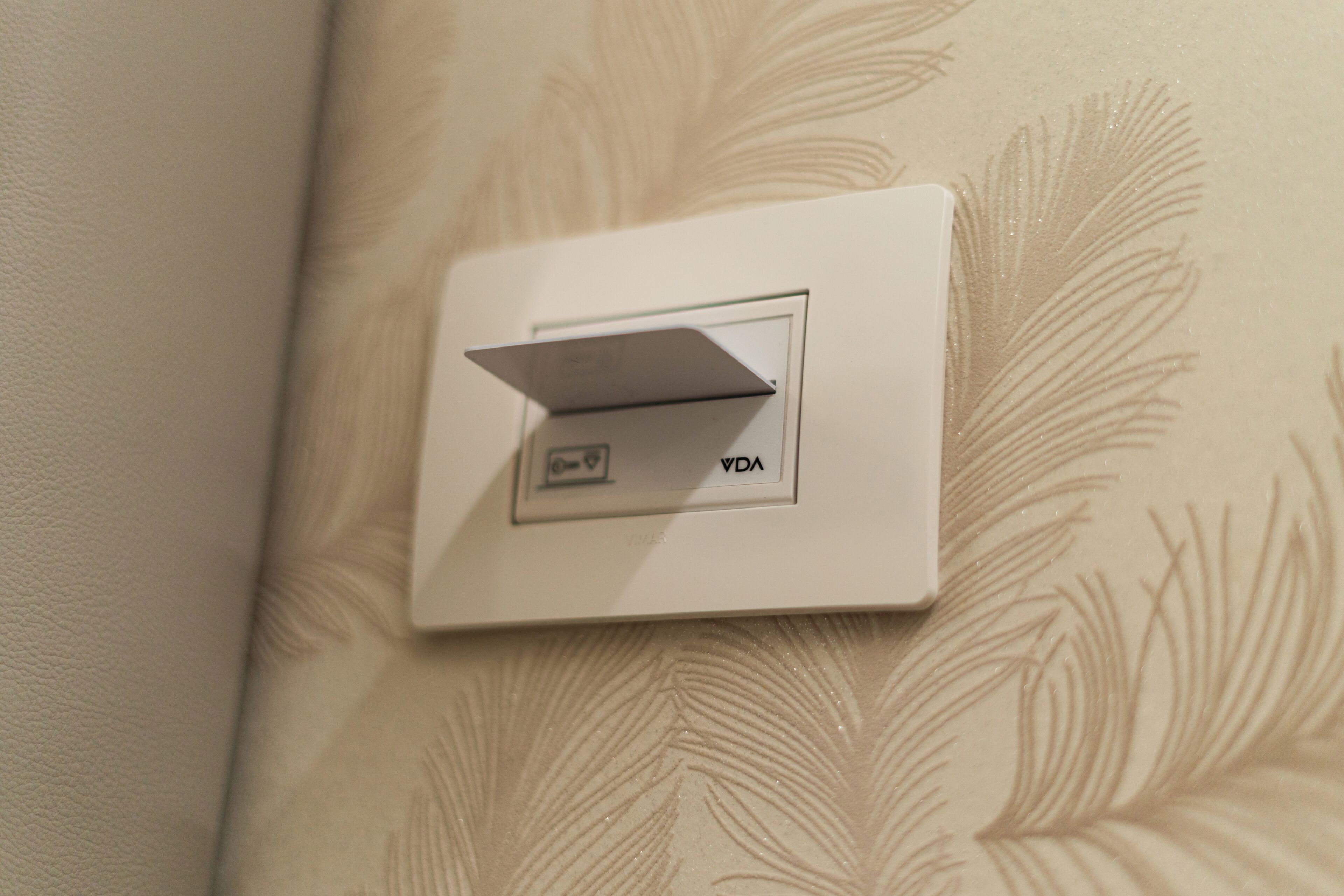 Ein Wandschalter mit dem Aufkleber 'VDA' an einer strukturierten Wand.
