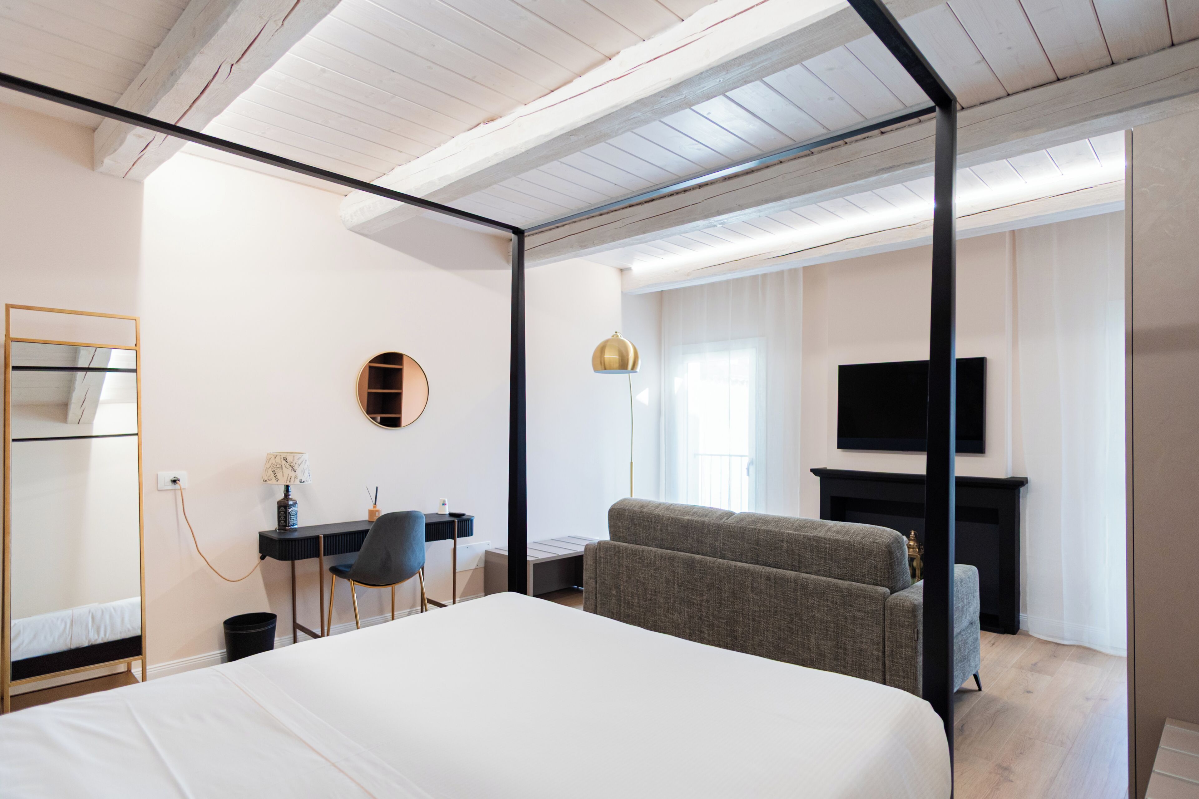 Una habitación de hotel moderna con una cama grande, un escritorio con una silla, un sofá, un televisor y una chimenea.