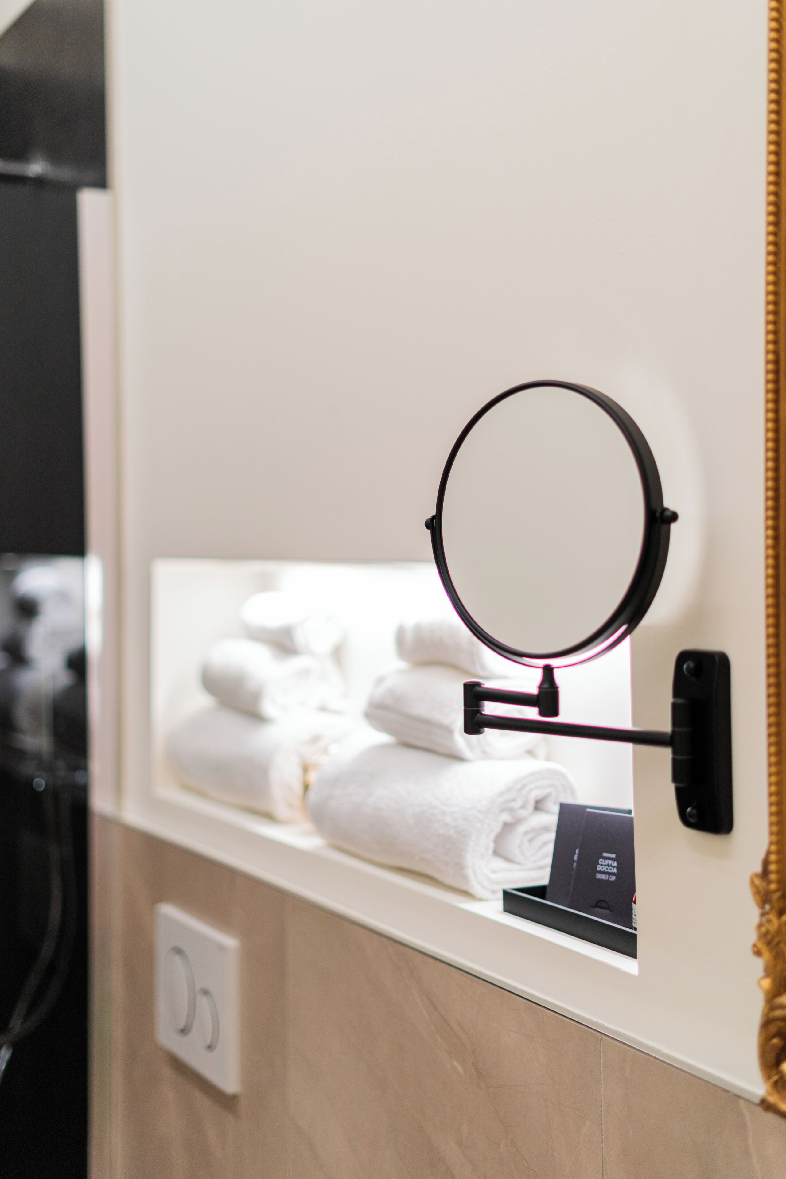 A bathroom with a mirror, towels, and a black device on the wall.