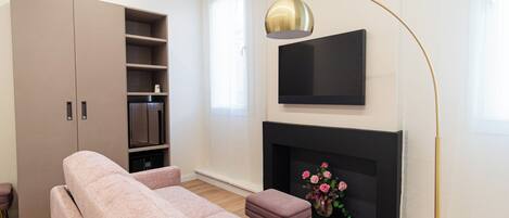 Una sala de estar moderna con un sofá, televisión, chimenea y una estantería.