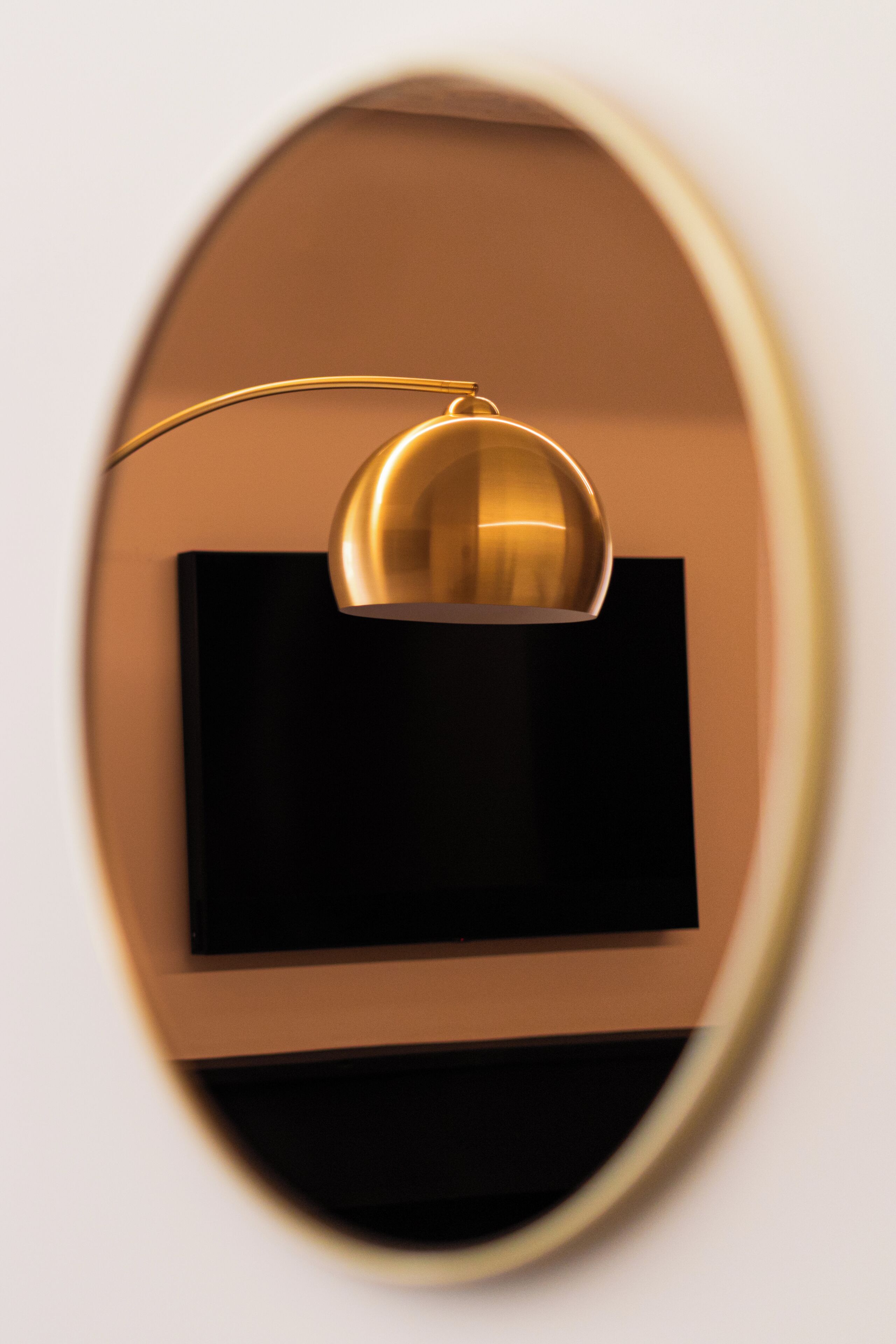 A modern, minimalist room with a black television mounted on a wall, a gold-framed mirror, and a simple, clean design.