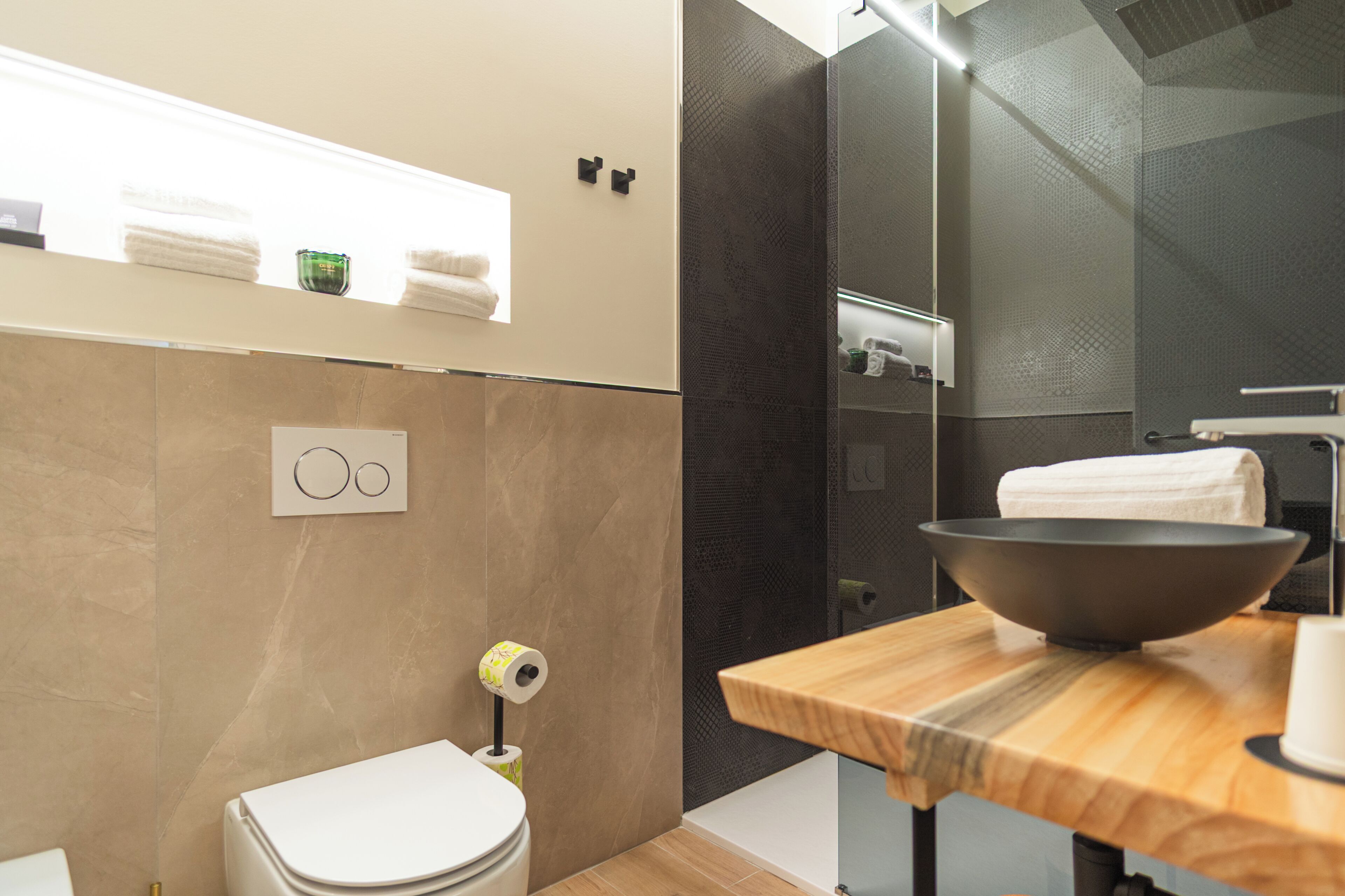 A modern bathroom with a toilet, a sink with a large bowl, and a shower area.