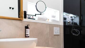 A bathroom with a white sink, a gold-framed mirror, a round mirror, and a bottle of Bio Lab soap.