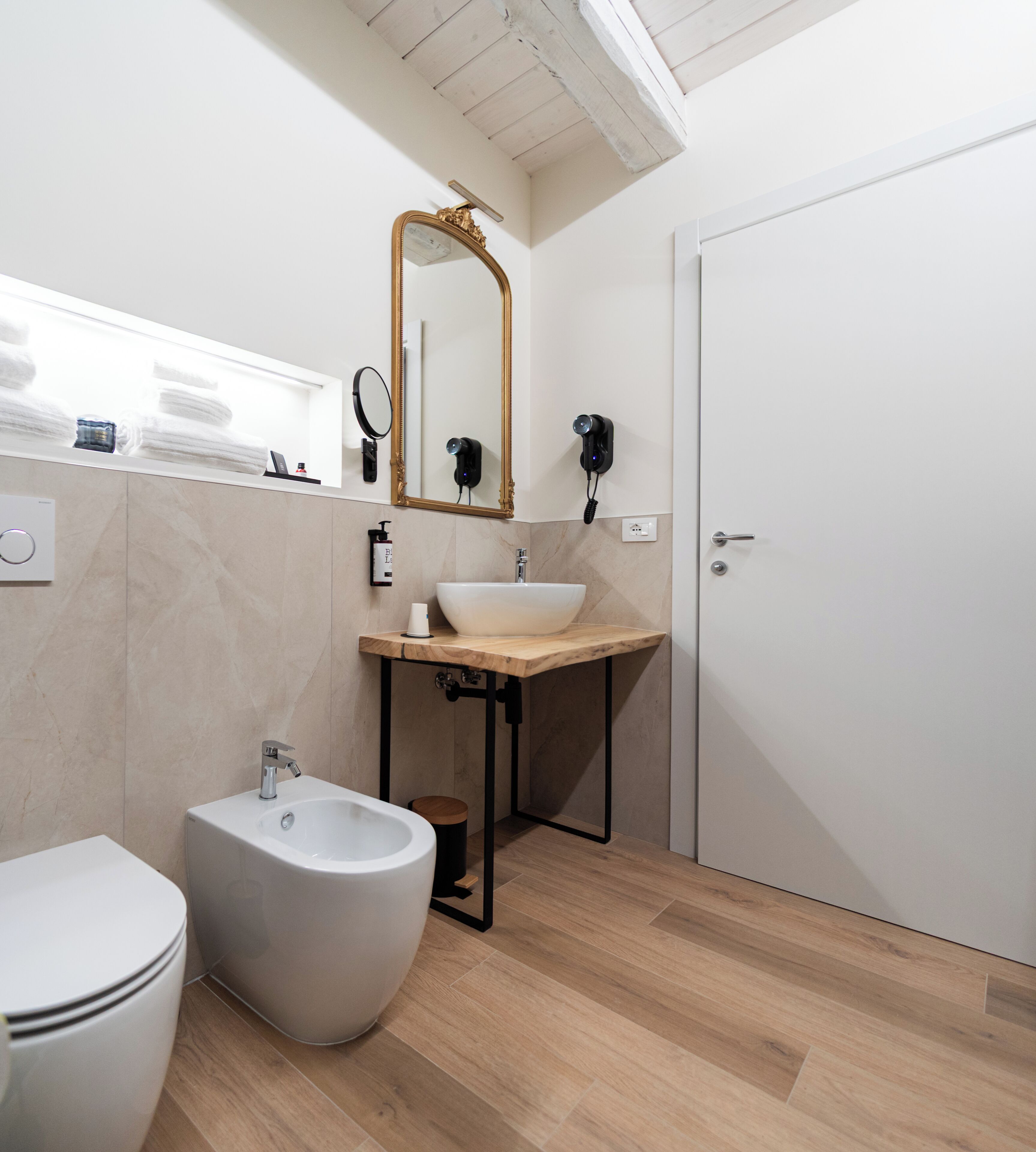 Une salle de bain moderne équipée d’un bidet, d’un lavabo, d’un miroir et de toilettes.