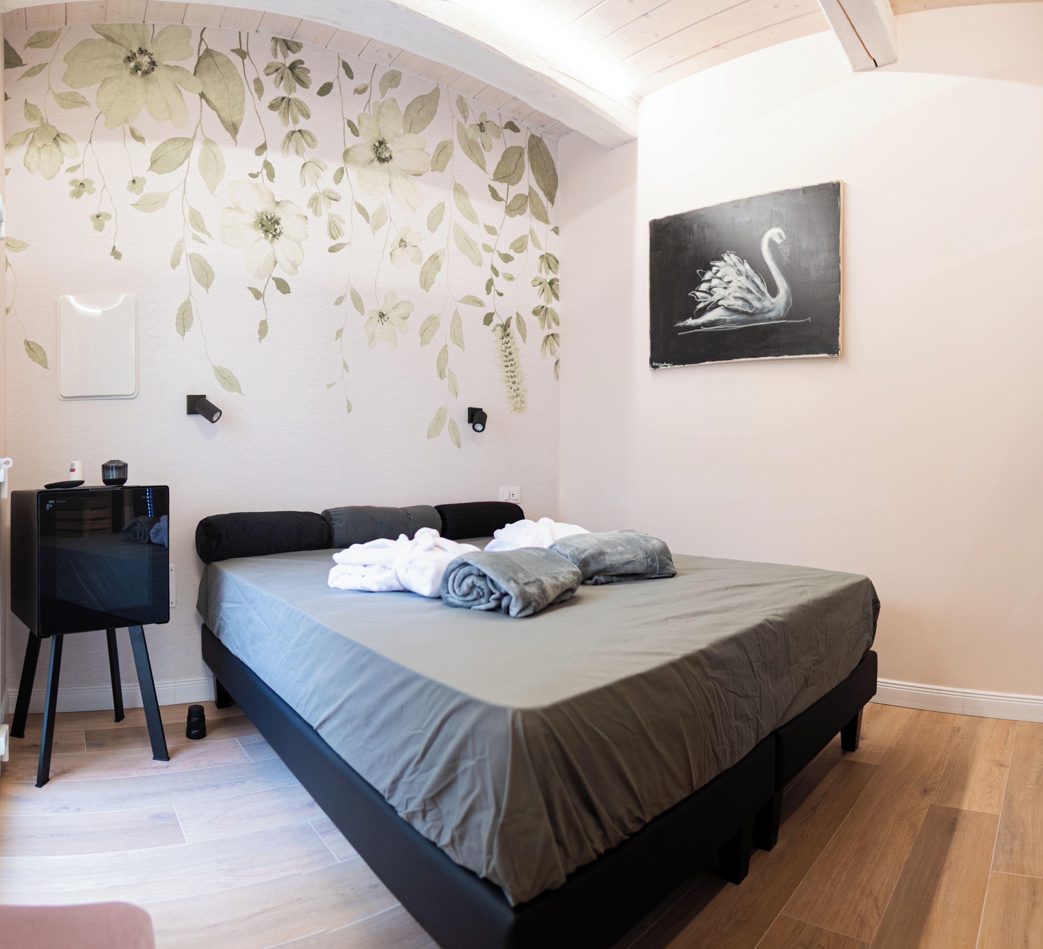 A bedroom with a bed, a desk, and a wall-mounted light.