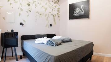 A bedroom with a bed, a desk, and a wall-mounted light.