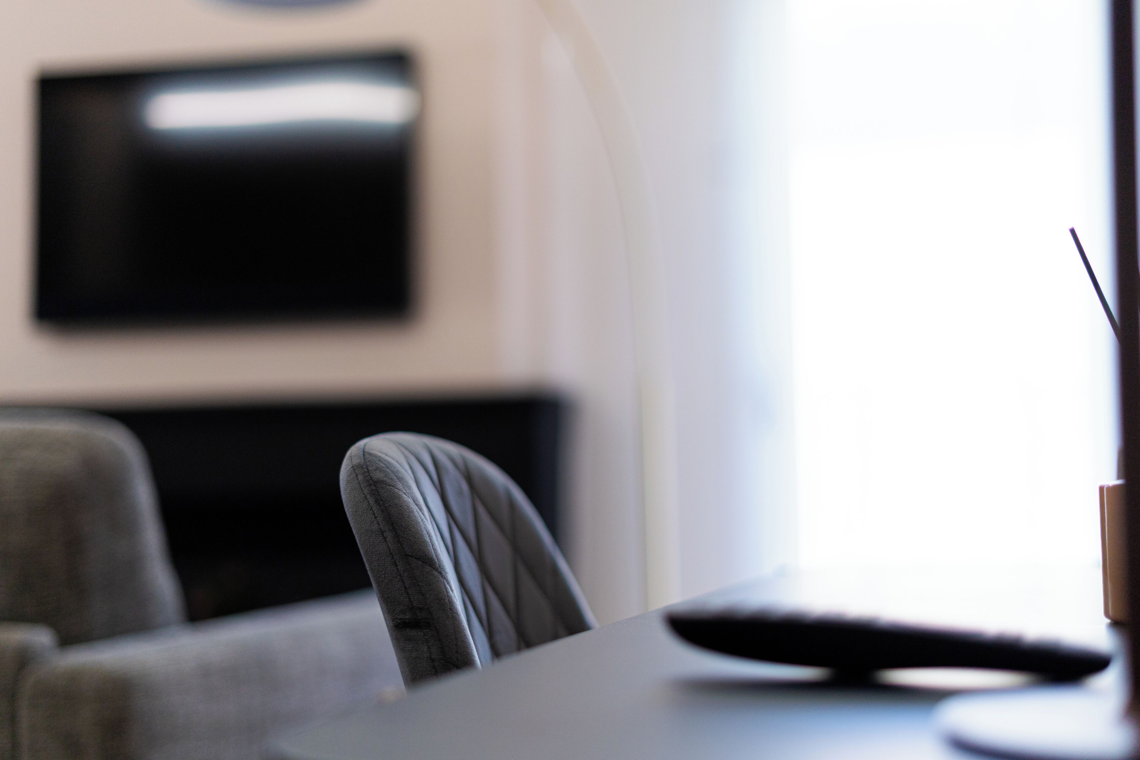 Una camera moderna con una TV a schermo piatto montata a parete, un divano grigio e un tavolino con un telecomando.