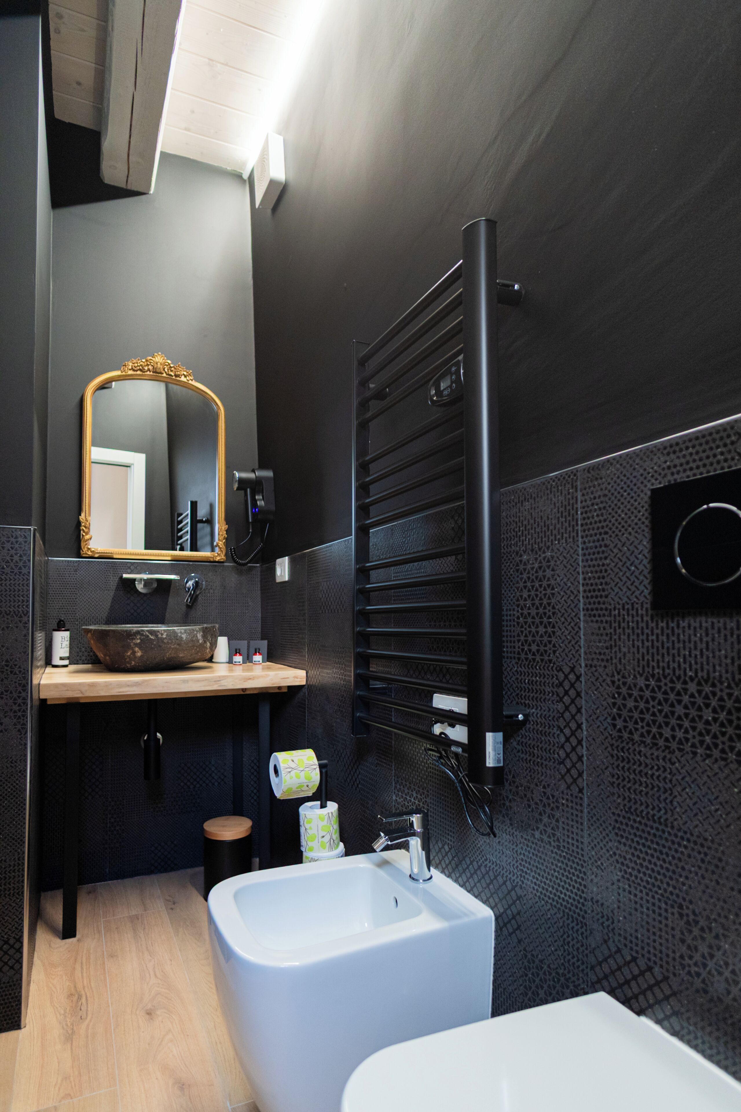 Ein modernes Badezimmer mit einem großen Spiegel, einem Holzhocker, einem weißen Waschbecken und einer Badewanne.