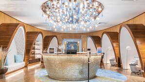 A lobby with a round reception desk, a chandelier, and a polished marble floor. - Spacious 3‑Bed Villa at Reserva Conchal (Cabo Velas)