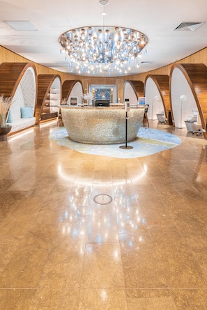 A lobby with a round reception desk, a chandelier, and a polished marble floor. - Spacious 3‑Bed Villa at Reserva Conchal (Cabo Velas)