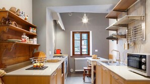 A compact kitchen with wooden shelves, a built-in oven, and a window with a view. - Room 'Unità 1' with Lake View, Wi-Fi, and Air Conditioning (Fratta)