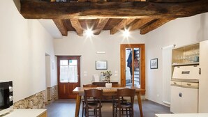 A dining area with a wooden table and chairs, a stone wall, and a white radiator. - Room 'Unità 1' with Lake View, Wi-Fi, and Air Conditioning (Fratta)