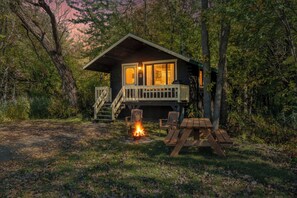 Une cabane dotée d’une terrasse, d’un foyer extérieur et de meubles de jardin.