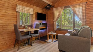 A cozy cabin interior with a wooden interior, a dining area, a sofa, and a fireplace. - Mini Chalet # 2  Domaine de l Archipel (Montérégie)
