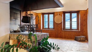 A rustic interior with a stone fireplace, wooden walls, and a large window. - Double and Twin Room 2 with Lake View, Wi-Fi, and Air Conditioning (Fratta)