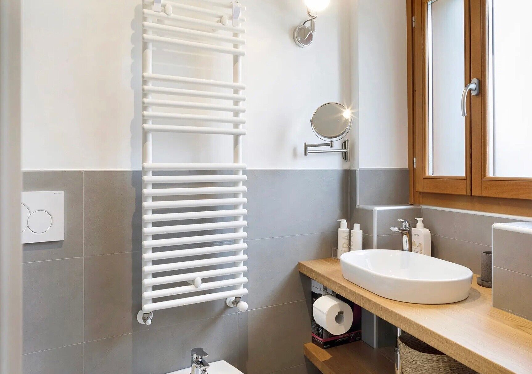 Une salle de bain avec un porte-serviettes blanc, un miroir, un lavabo et des articles de toilette.