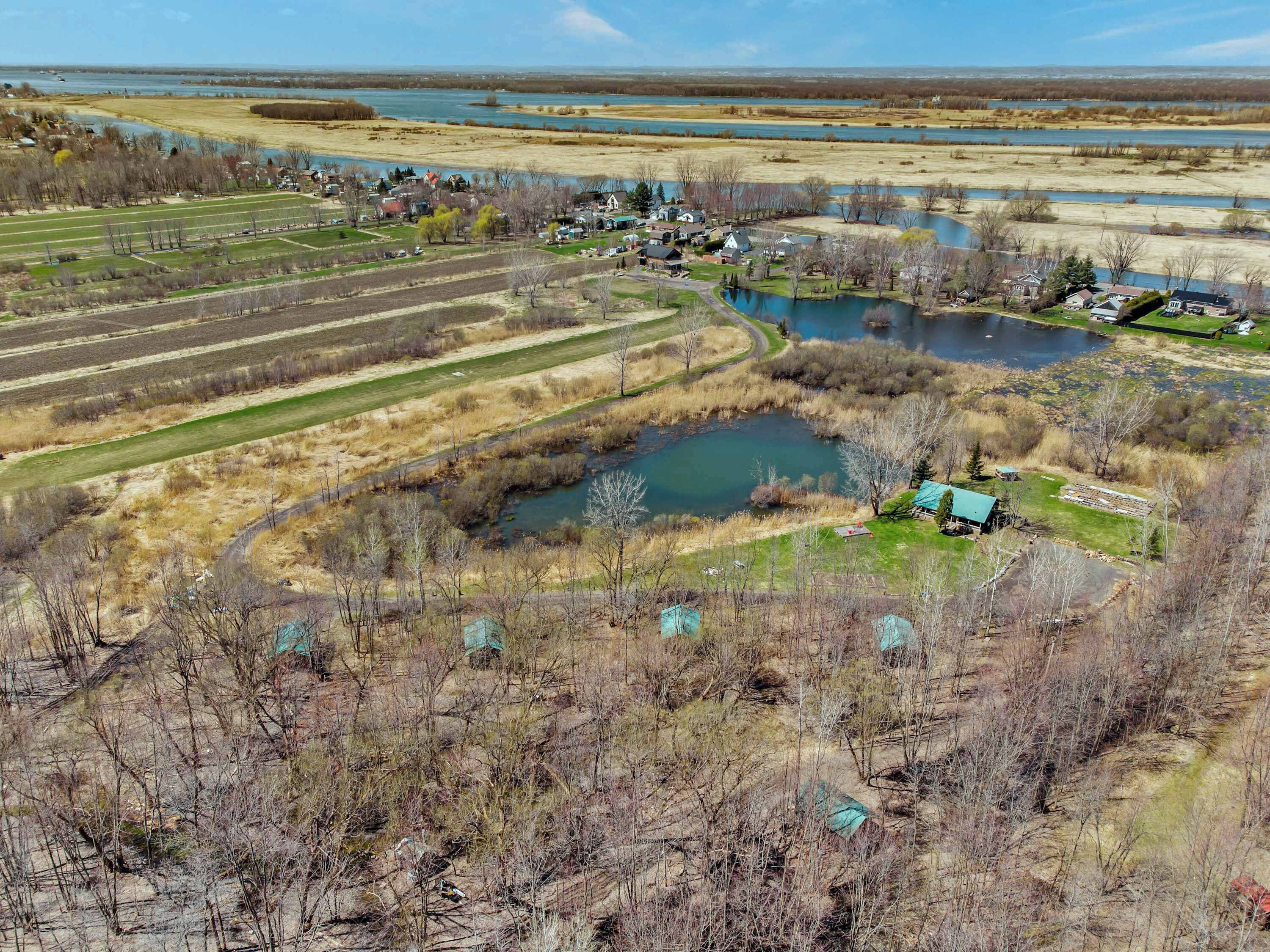 Paesaggio rurale con un piccolo lago, campi e alcune case.