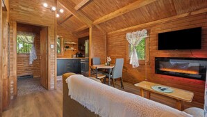 A cozy cabin interior with a dining area, kitchen, and a fireplace.