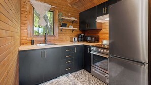 A compact kitchen with dark cabinets, a stainless steel refrigerator, a stove, and a microwave.
