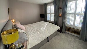 Une chambre à coucher avec un lit, une lampe de chevet et une fenêtre avec des rideaux.