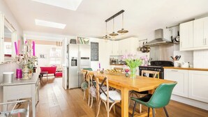 Une cuisine moderne avec des meubles blancs, une table à manger en bois et une chaise rouge.