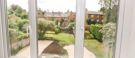 A view through a window with a garden and houses in the background.