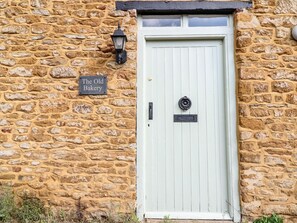 Un bâtiment en pierre avec une porte blanche et une enseigne indiquant « L’ancienne boulangerie ».