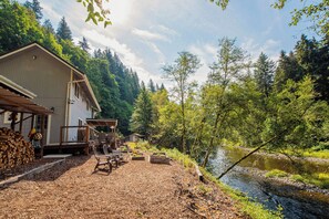 A cabin with a deck, outdoor seating, and a river view.