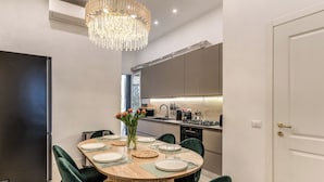 Een moderne keuken met een centraal eiland, een eetgedeelte met een ronde tafel en een kroonluchter.