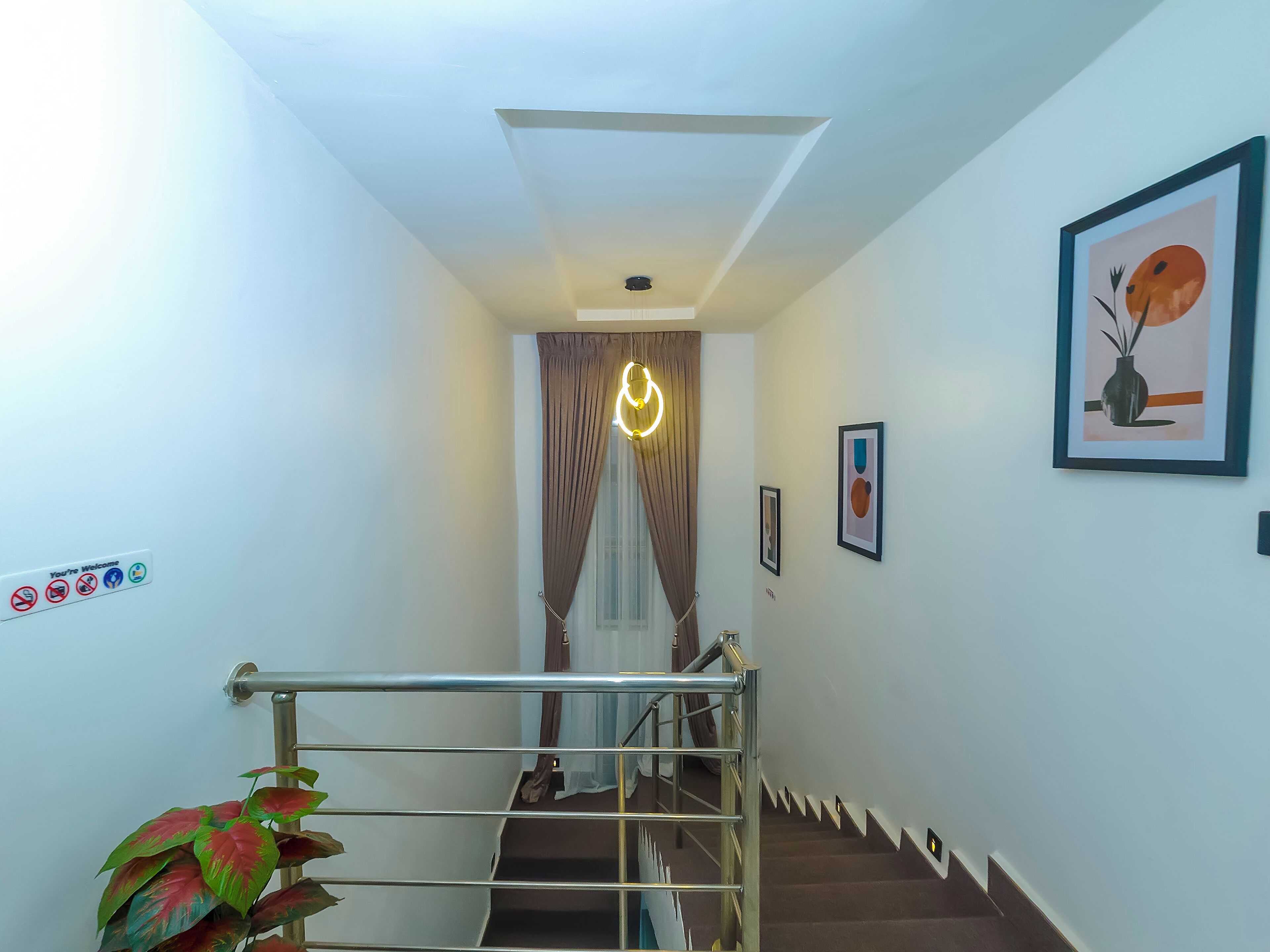 A staircase with a metal handrail, a wall-mounted light fixture, and a framed picture.