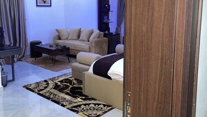 A modern living room with a sofa, a coffee table, and a rug. There is a wooden door frame visible. - Morgan Hill Residence (Abuja)