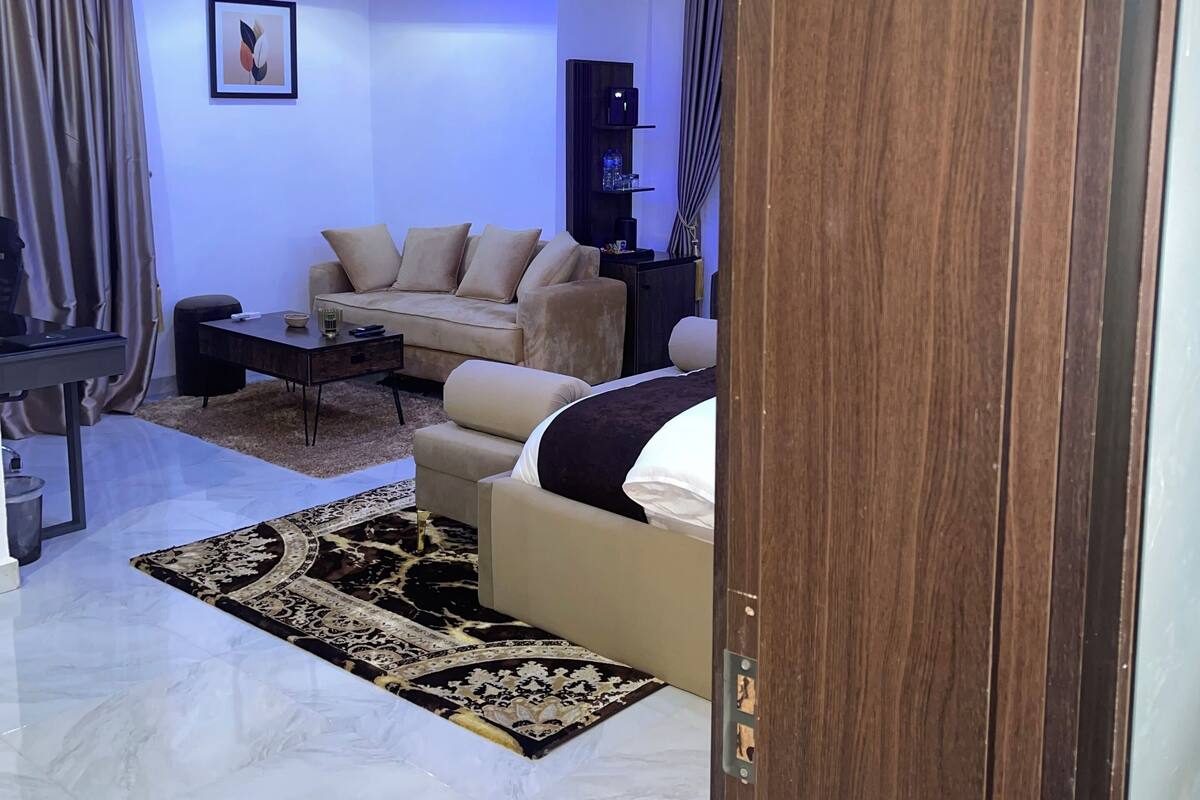 Un salon moderne avec un canapé, une table basse et un tapis. On peut voir un cadre de porte en bois.