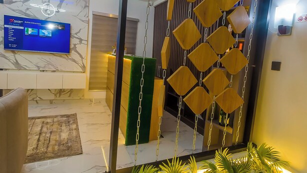 A modern reception area with a digital screen displaying room options, a reception desk, and a decorative hanging element. - Morgan Hill Residence (Abuja)
