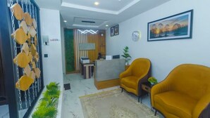 A modern living room with two yellow armchairs, a reception desk, and a painting on the wall. - Morgan Hill Residence (Abuja)