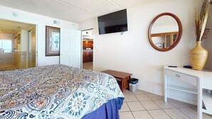 Una camera da letto con un letto, una televisione, uno specchio, una scrivania e un cestino.