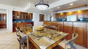 Un'ampia cucina con armadietti in legno, un tavolo da pranzo con piano in vetro e un lampadario.