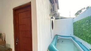 A room with a wooden door, a white wall, and a green wall with a plant. - Capital O 94840 Unihomestay Malioboro (Yogyakarta)