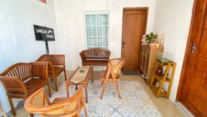 A cozy room with a wooden sofa set, a small table, and a decorative shelf with items. A sign on the wall reads "UNIQUE HOME". - Capital O 94840 Unihomestay Malioboro (Yogyakarta)