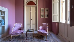 Una habitación con dos sillas ornamentales, una mesita pequeña y un amplio arco de entrada.