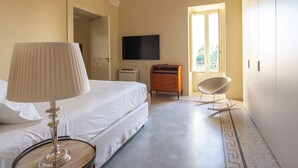 Habitación de hotel con cama, televisor, cómoda, mecedora y ventana con vista.