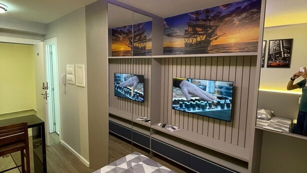 A hotel room with a bed, two TVs mounted on the wall, a desk, and a chair. - Studio with swimming pool near to the Malls. (Curitiba)