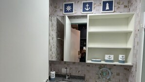 A compact bathroom with a sink, toilet, and a shelf above the toilet. - Studio with swimming pool near to the Malls. (Curitiba)