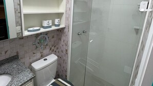 A bathroom with a toilet, a shower, and a sink. There are shelves above the toilet and a towel rack above the shower. - Studio with swimming pool near to the Malls. (Curitiba)