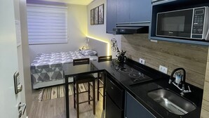 A compact kitchen with a built-in microwave, a sink, and a small dining area with a table and chairs. - Studio with swimming pool near to the Malls. (Curitiba)