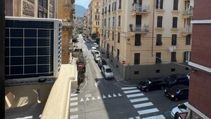 Vista de una calle con edificios de varios pisos, un paso de peatones y coches estacionados.