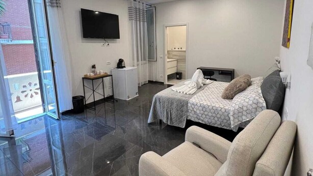 Una habitación de hotel moderna con cama, sofá, televisor y baño.