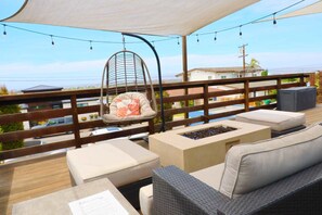 Une terrasse dotée de meubles en osier, d’un fauteuil suspendu et d’une table avec un jeu d’échecs.
