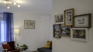 Un salon avec un canapé, un fauteuil, une lampe et des tableaux encadrés accrochés au mur.